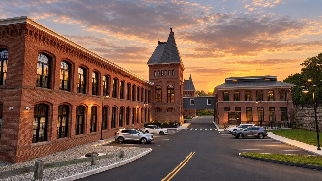 Restored brick mill building with turret towers and parking area at South Mill Lofts during sunset