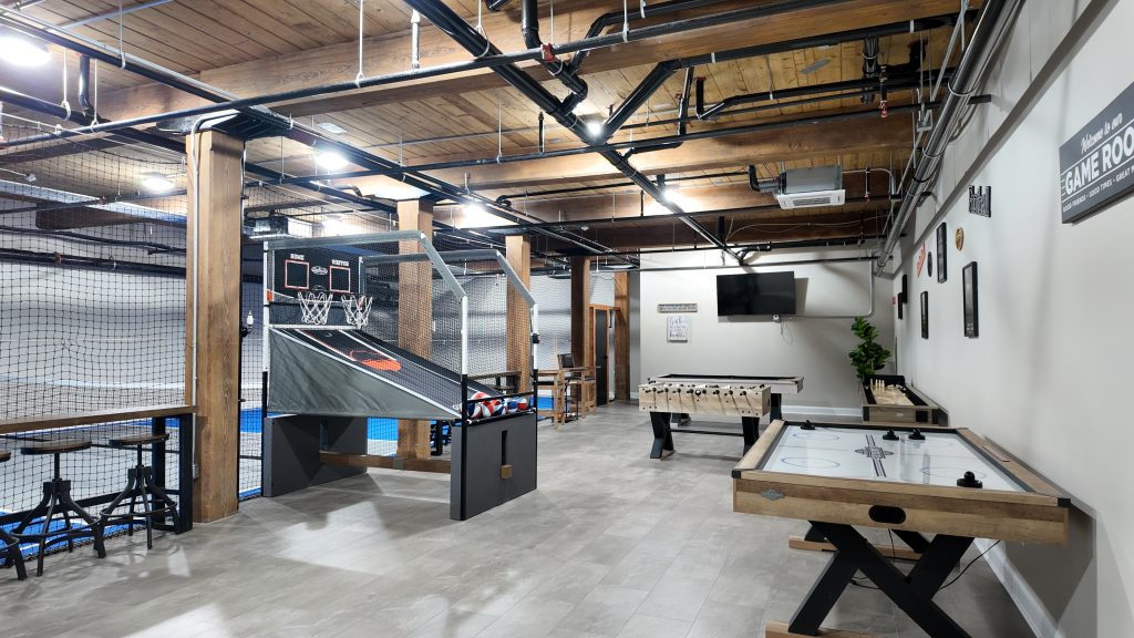 Game room at South Mill Lofts with arcade basketball, foosball, air hockey, and exposed timber ceiling