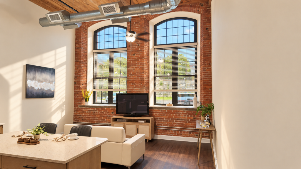 Living room with exposed brick walls, arched windows, wood floors, and a ceiling fan under exposed ductwork